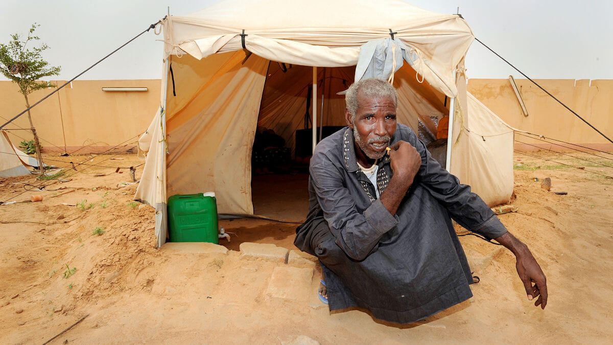 Ein Mann sitzt vor einem Flüchtlingszelt.