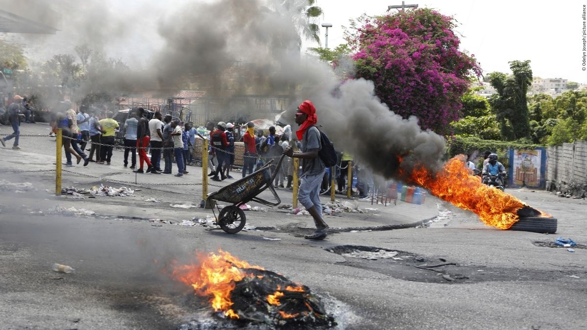 Ein Mann schiebt eine Schubkarre an brennenden Reifen vorbei, während er den Rücktritt von Premierminister Ariel Henry fordert, in Port-au-Prince, Haiti © Odelyn Joseph/picture alliance