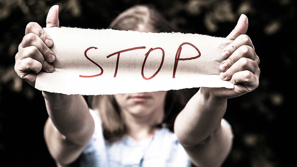 Mädchen hält Banner mit dem Wort "Stop" vor ihr Gesicht