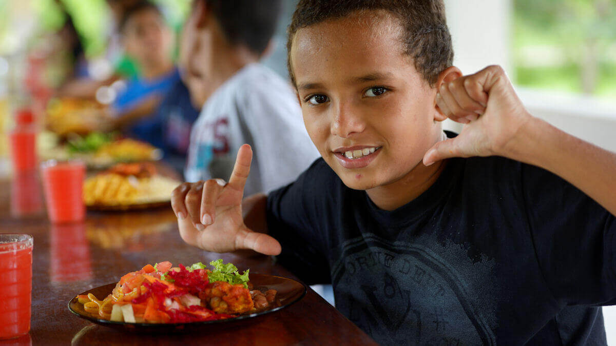 Ein Junge sitzt vor einem Teller mit einem gesunden Mittagessen