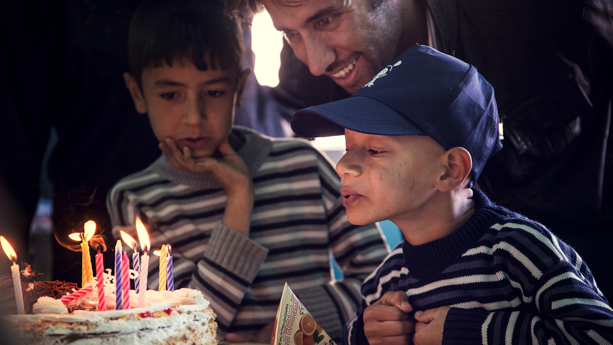 Kind pustet Kerzen auf einer Torte aus