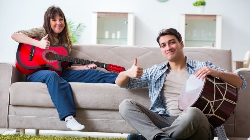 Frau und Mann spielen ein Instrument im Wohnzimmer