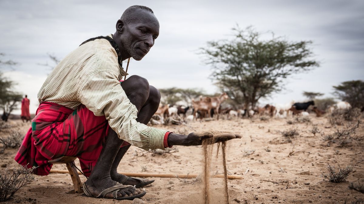 Mann zeigt die extreme Trockenheit auf einem kenianischen Feld