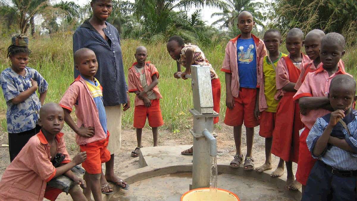 Eine Gruppe von Kinder und Jugendlichen steht um einen Brunnen