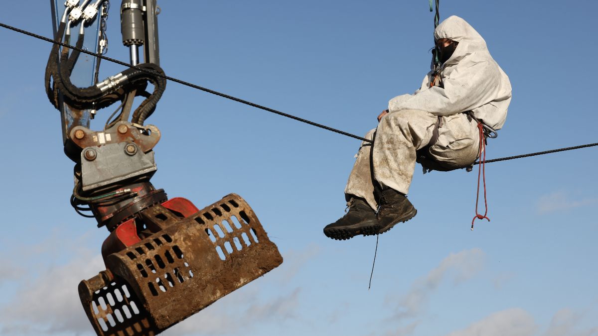 Lützerath: Aktivist auf einem Seil in der Luft nahe einer Baggerschaufel hängend